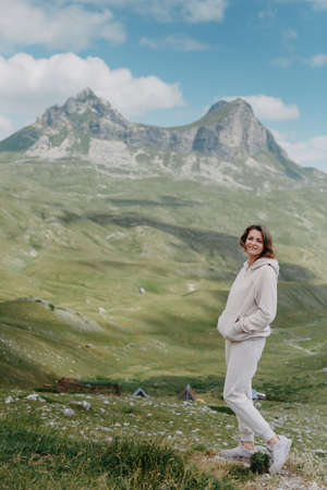 Hiker tourist girl standing on top of the mountain and enjoying valley view. Happy woman with her arms outstretched, freedom and happiness, achievement in mountainsの写真素材