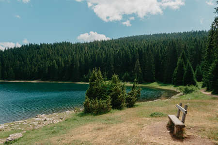 Relax. Rest near lake. Wooden bench overlooking the lake and mountains. Beautiful mystical lake. Black Lake, Durmitor National Park. Montenegroの写真素材