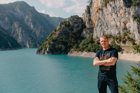 Handsome young man on a lakes shore at dusk of a sunny, peaceful day, A man standing at the stone...