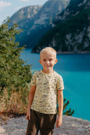 Boy young traveler on the background The famous Piva Canyon with its fantastic reservoir. View of road above Piva Lake (Pivsko Jezero) in Montenegro. Kid looks at river Piva, Montenegro.の写真素材
