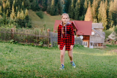 Little girl look into the distance on a grassy hill. portrait of a girl against the panorama of the Alps. happy children girl on spring flowers meadow.の写真素材