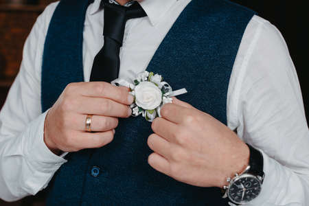 Morning of the groom. Groom morning preparation. Young and handsome groom getting dressed in a wedding shirtの写真素材