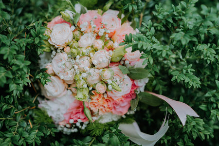 Look from above at white nd pink wedding bouquet of flowers lying on the bush. A beautiful bridal bouquet of white roses lies on a green bush. Soft focus.の写真素材