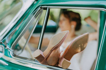 Wedding bride rest and have fun on green vintage retro car after wedding. Honeymoon concept. Car woman happy in old retro vintage car. Young woman driving on road trip on beautiful sunny summer day.の写真素材