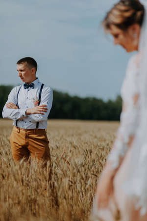 fashionable and happy wedding couple at wheat field at sunny day. Bride and groom kissing in a wheat field. Young beautiful wedding couple hugging in a field with grass eared.の写真素材