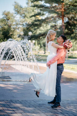 Happy bride and groom on wedding walk near fountain. Bride and groom having a romantic moment on their wedding day.の写真素材