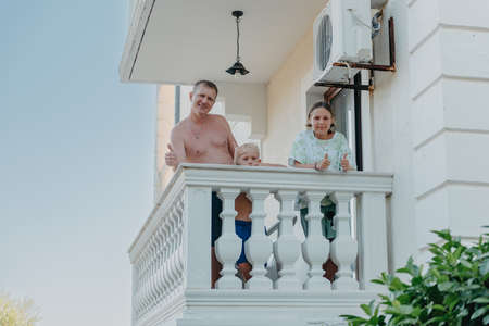Family of three people on hotel balcony in summer enjoying their vacation.の写真素材