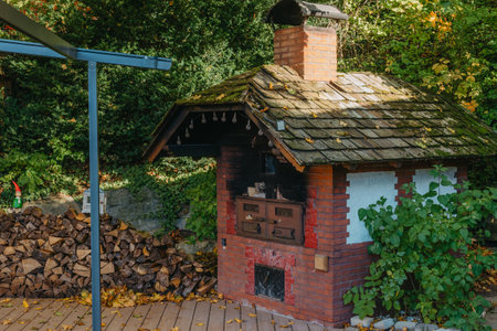 An Old Stove And Firewood For It In The Yard In The Village. Old Stone Fireplace Outdoors In The Fall. Traditional Brick Oven With Wood For Baking Bread Outdoor In Europe.の写真素材