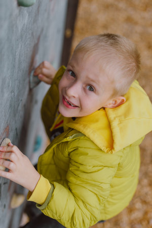 Boy At The Climbing Wall Without A Helmet, Danger At The Climbing Wall. Little Boy Climbing A Rock Wall Indoorの写真素材