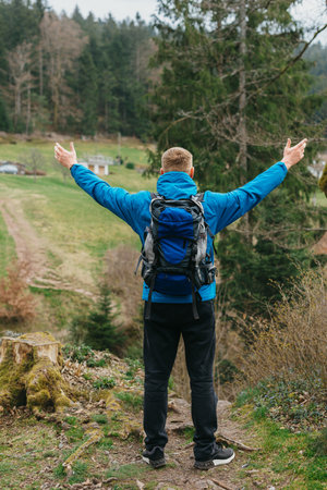 Traveler Man with backpack mountaineering Travel Lifestyle concept mountains on background Summer trip vacations outdoor. Concept of travel and healthy, active lifestyle. Young guy with dreadlocks went hiking in mountains. Man with yellow backpack stands on top of hill and enjoys views of nature. A guy tourist with a backpack stands on a mountain trail and looks into the distance. The concept of travel and adventure.の写真素材