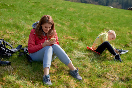 Young tourist girl resting with phone on the top of the mounting landscape. Hiking woman relaxing. Caucasian beautiful woman wearing casual clothes, adventure traveling alone and hiking on the top of mountains in vacation trip on weekend.の写真素材