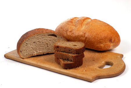 Bread lies on a wooden cutting board next to a knife on a white background.の写真素材