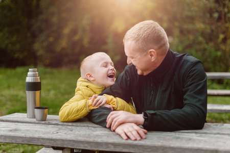Happy Family: Father And Child Boy Son Playing And Laughing In Autumn Park, Sitting On Wooden Bench And Table.の写真素材