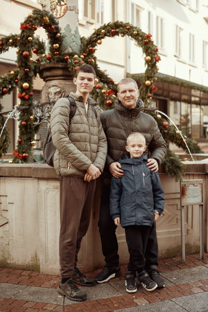 Joyful Family Portrait: Father and Two Sons by Festive Vintage Fountain.