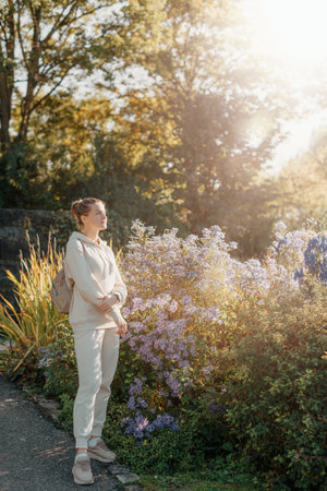 Beautiful elegant woman standing in autumn park with yellow leaves outdoor. Beauty Romantic Girl Outdoors enjoy autumn yellow leaves. Portrait of joyful woman in park during fall. Happy nature. Sun light on sunset. Warm toned art work. Portrait of romantic femaleの写真素材