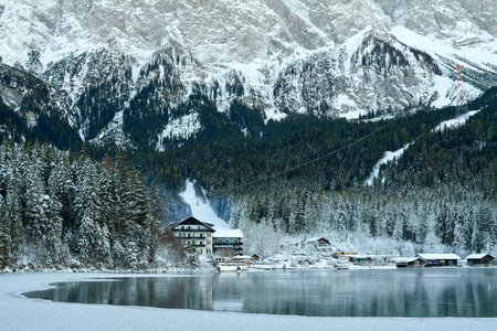 Picturesque Winter Village in Bavarian Alps: Eibsee Lake and Zugspitze Mountain Panorama with Snow-Covered Chalets and Ski Resortの写真素材