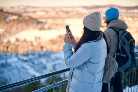 Capturing Urban Moments: Woman Tourist Takes Smartphone Photo of City Skyline on Sunny Day