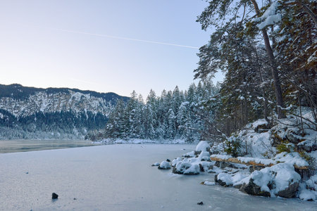 Breathtaking Alpine Winter Wonderland: Majestic Mountain Reflects in Frozen Lake Amidst Snowy...