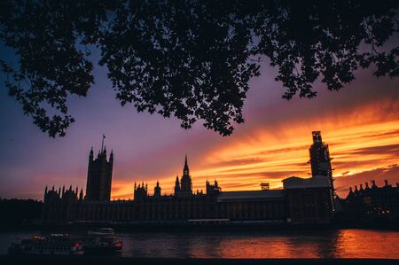 House of parliament and Big Ben in summer evening, colorful orange sky. Symbol of London, Britain,...