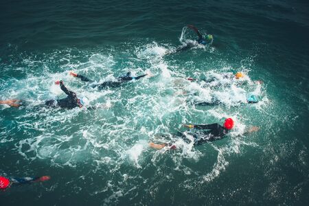 Triathlon swimmers churning up the water.. Athletes practicing for triathletic race in lakの写真素材