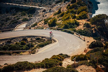 Cyclist on the road in mediterranean landscape. Orange color filter.の写真素材