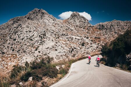Man and woman ride together on road bicycle.. Adventure in big mountainsの写真素材