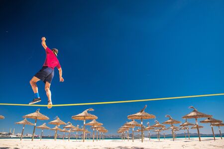 Young man doing slackline on the beautiful summer tropical beach.. Active life sport photo