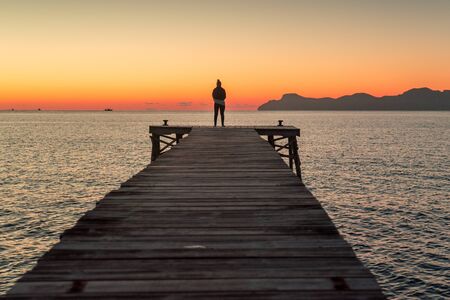 Alone woman standing on the pier by the .sea in summer sunrise landscapeの写真素材