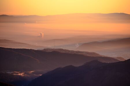 Sunrise in mountains, shape of hills in morning mist, white edit space