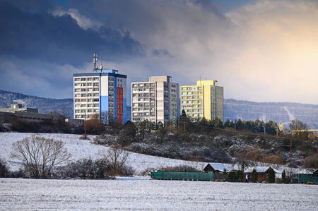Block of flats in winter landscape, blue background, dark sky