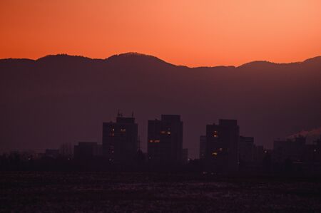 Block of flats silhouette in orange sunrise light. City in the morningの写真素材