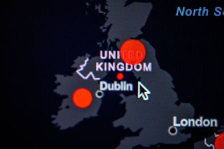 Great Britain, Ireland, United Kingdom. Coronavirus COVID-19 global cases Map. Red Dot showing the number of infected. Johns Hopkins University map on monitor display.の写真素材