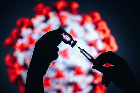 Coronavirus Covid-19 Protection and Vaccine. syringe with glass bottle for vaccination in hand in...