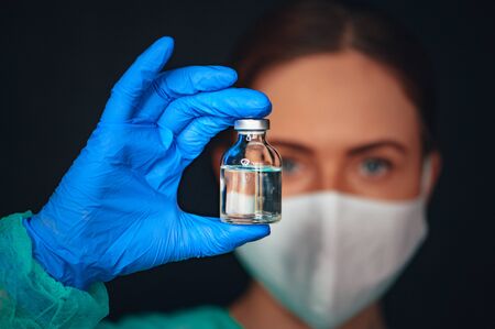 Coronavirus Covid-19 Protection and Vaccine. Biological hazard. Epidemic of the Chinese coronavirus. An asian woman in a protective suit and mask holds injection syringe Flu, coronavirus, ebola, TB.の写真素材