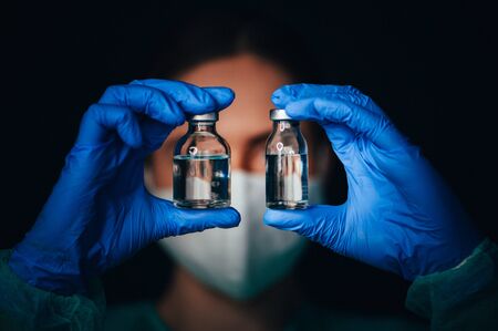 Coronavirus Covid-19 Protection and Vaccine. Female doctor holds medical glasses of Vaccine from, flu, coronavirus, ebola, TB.の写真素材