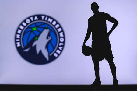 NEW YORK, USA, JUN 18, 2020: Minnesota Timberwolves logo of professional basketball club in american league. Silhouette of basket player in foreground. Sport concept photo, edit space.のeditorial素材