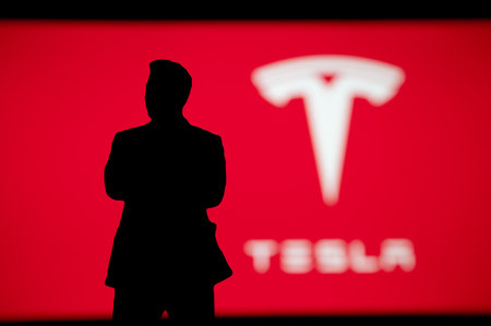 NEW YORK, USA, OCTOBER 2, 2022: Elon Musk businessman silhouette on Tesla presentation, Logo of company on red backgroundのeditorial素材