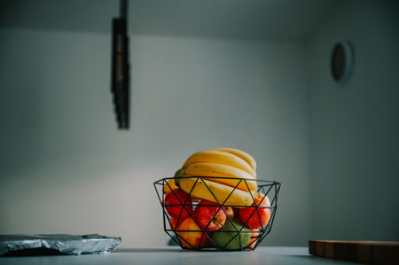Illuminated by natural light, a banana sits in a glass bowl on the kitchen counter.の写真素材