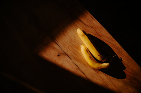 A sunny kitchen moment: banana placed on the table. Dark shadowの写真素材