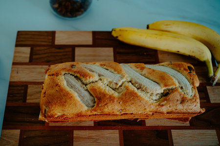 Natural light highlights a banana bread and fresh banana on the kitchen surfaceの写真素材