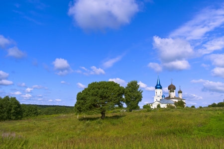 Church building in a huge green field under high  blue sky with white clouds. Ivanishche Tver Provinceの写真素材