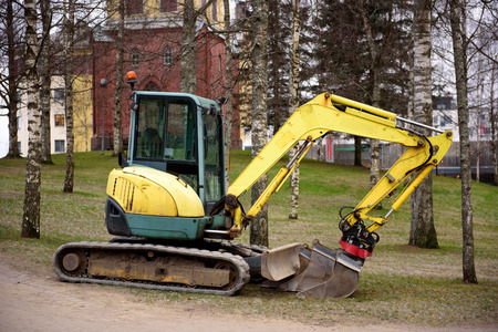 Mini excavator at a construction site. The excavator stands near the dug hole