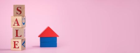 Red word SALE is lined with wooden cubes and small house made of wood, on pink background with space for text. Concept selling real estate on credit or mortgage in financial market on Black Fridayの写真素材