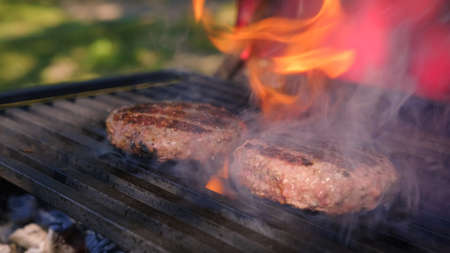 Beef or pork meat barbecue burgers for hamburger prepared grilled on bbq fire flame grill. Tasty meat for burger cooked on fiery barbecue grill. Close up of chief cooked oil unhealthy.の写真素材