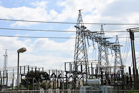 High voltage power lines with electricity pylons at blue sky.