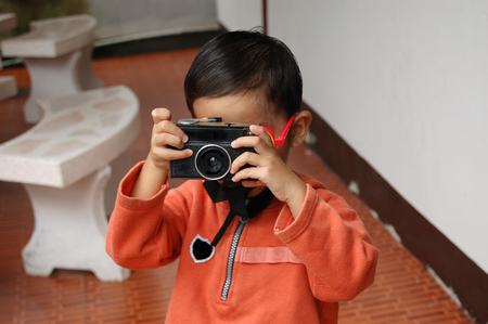 Little boy taking picture using vintage film cameraの写真素材