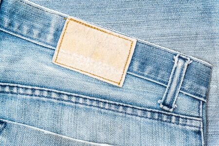 closeup of blank grungy leather label on worn blue denim with orange seamsの写真素材