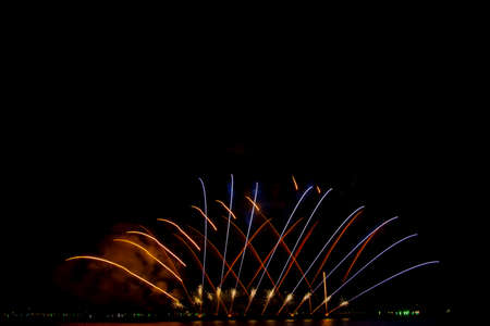 colorful fireworks,Beautiful multi color fireworks explosions lighting sky over trees silhouette and over an illuminated,celebration conceptの写真素材