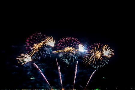 colorful fireworks,Beautiful multi color fireworks explosions lighting sky over trees silhouette and over an illuminated,celebration conceptの写真素材