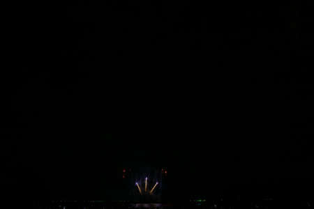 Beautiful multi color fireworks explosions lighting sky over trees silhouette and over an illuminated,colorful fireworks celebration conceptの写真素材